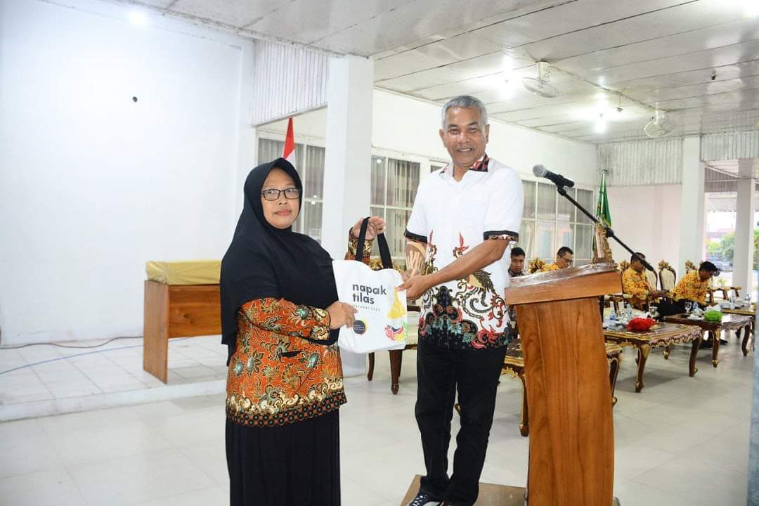 Gambar Bupati Ketapang Martin Rantan Saat Memberikan Tas bertuliskan "Napak Tilas" Kepada Salah Satu Tenaga Kontrak Guru. (IS)